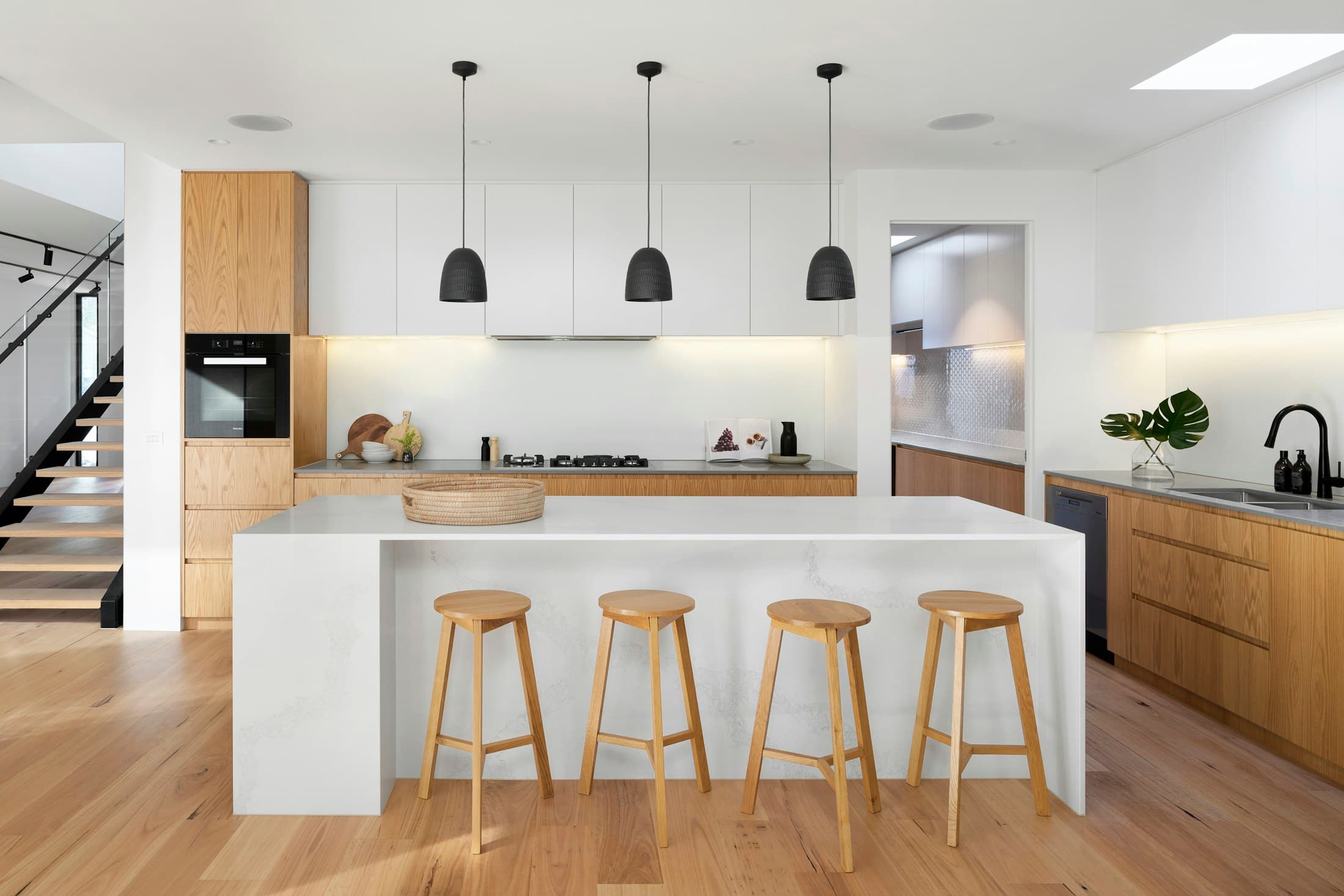 Bright kitchen with a white stone island, timber cabinetry and pendant lights