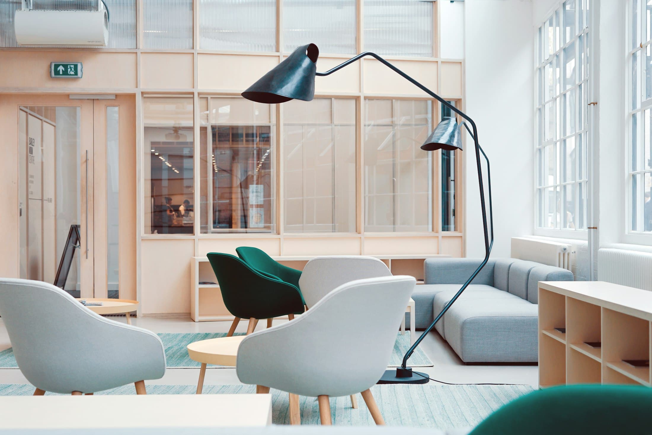 Breakout lounge with soft seating, timber-framed glazing and a reading lamp