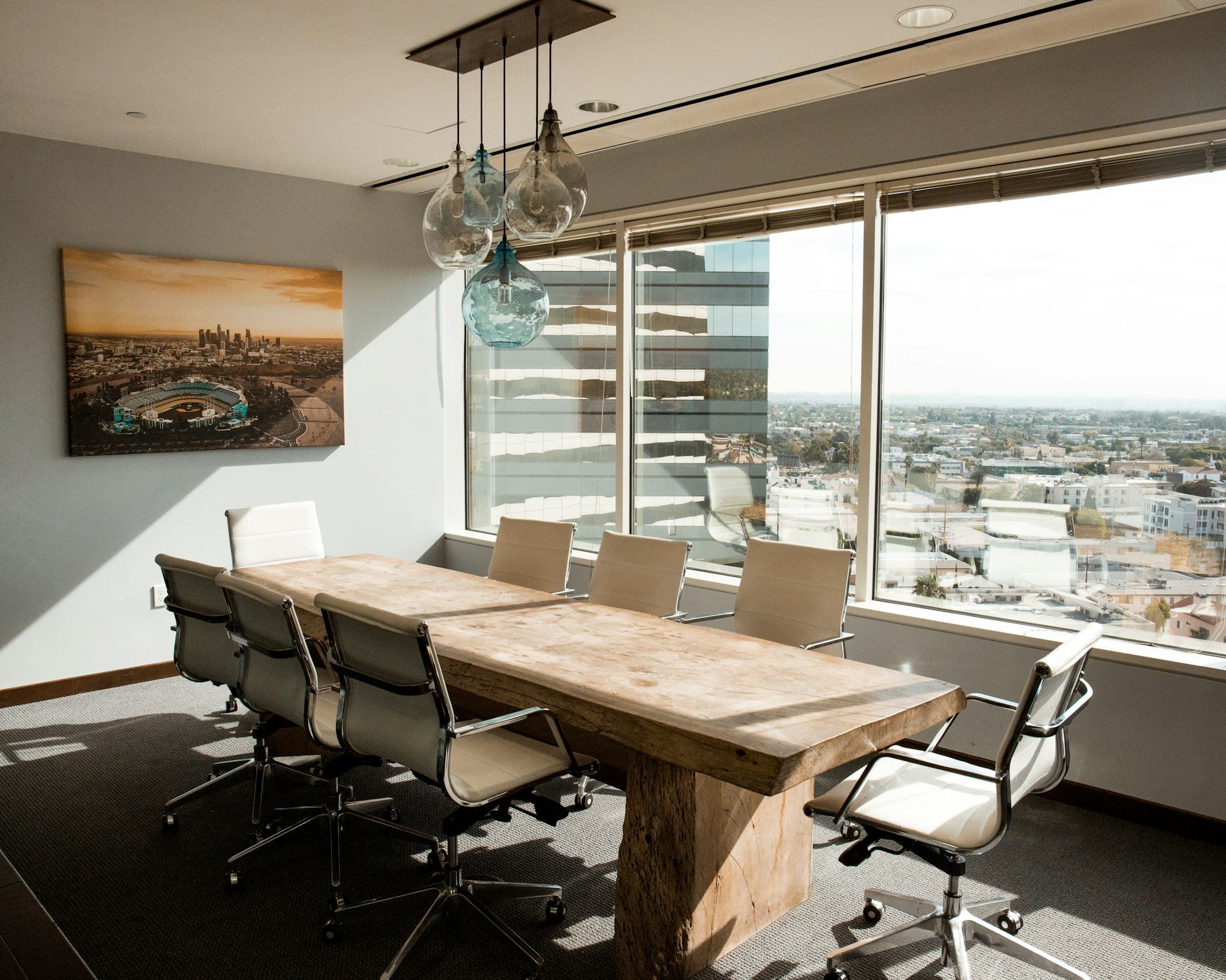 Meeting room with a solid timber table, office chairs and wide windows overlooking the city