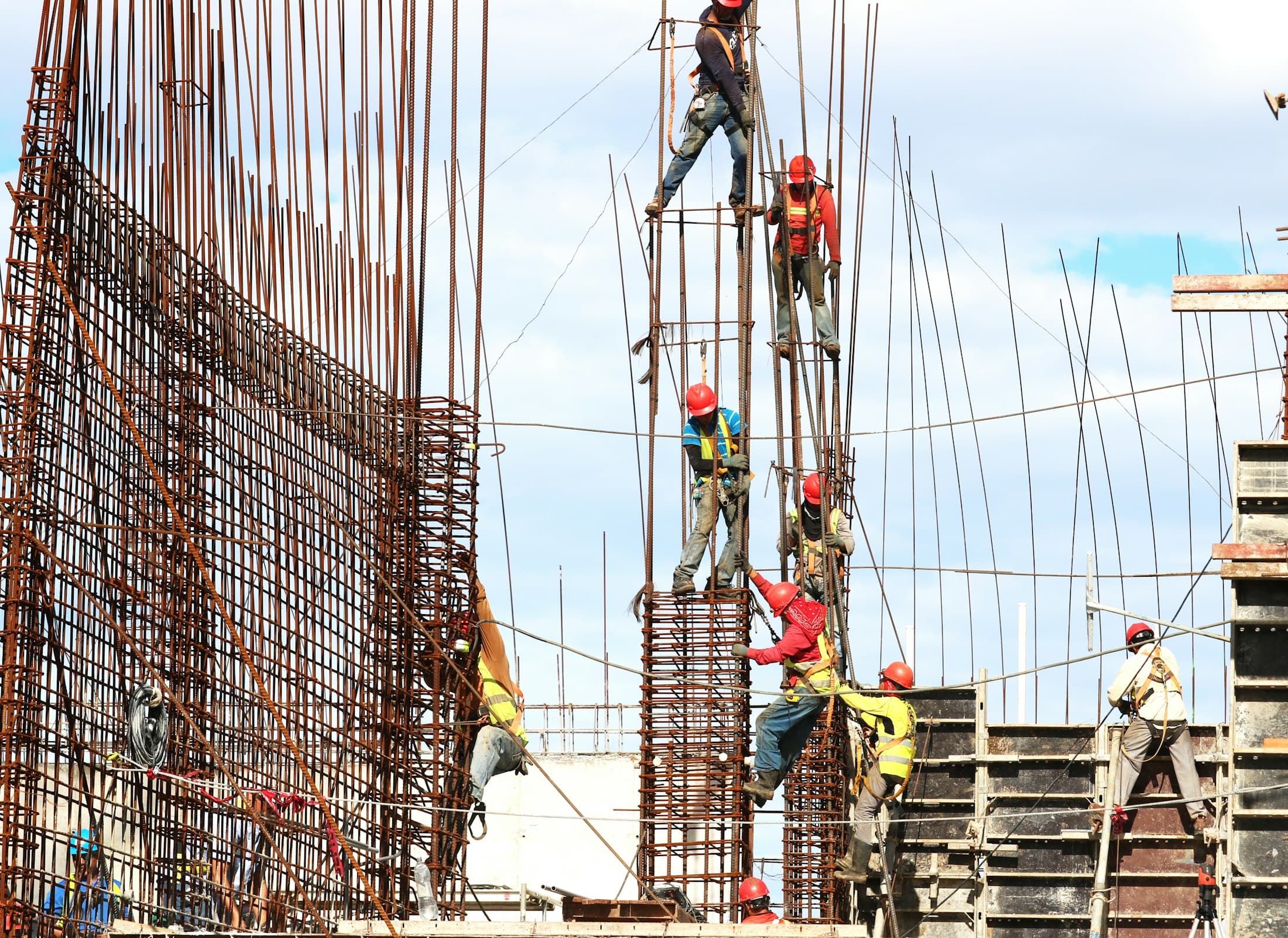 Builders on scaffolding fixing steel reinforcement for a concrete frame