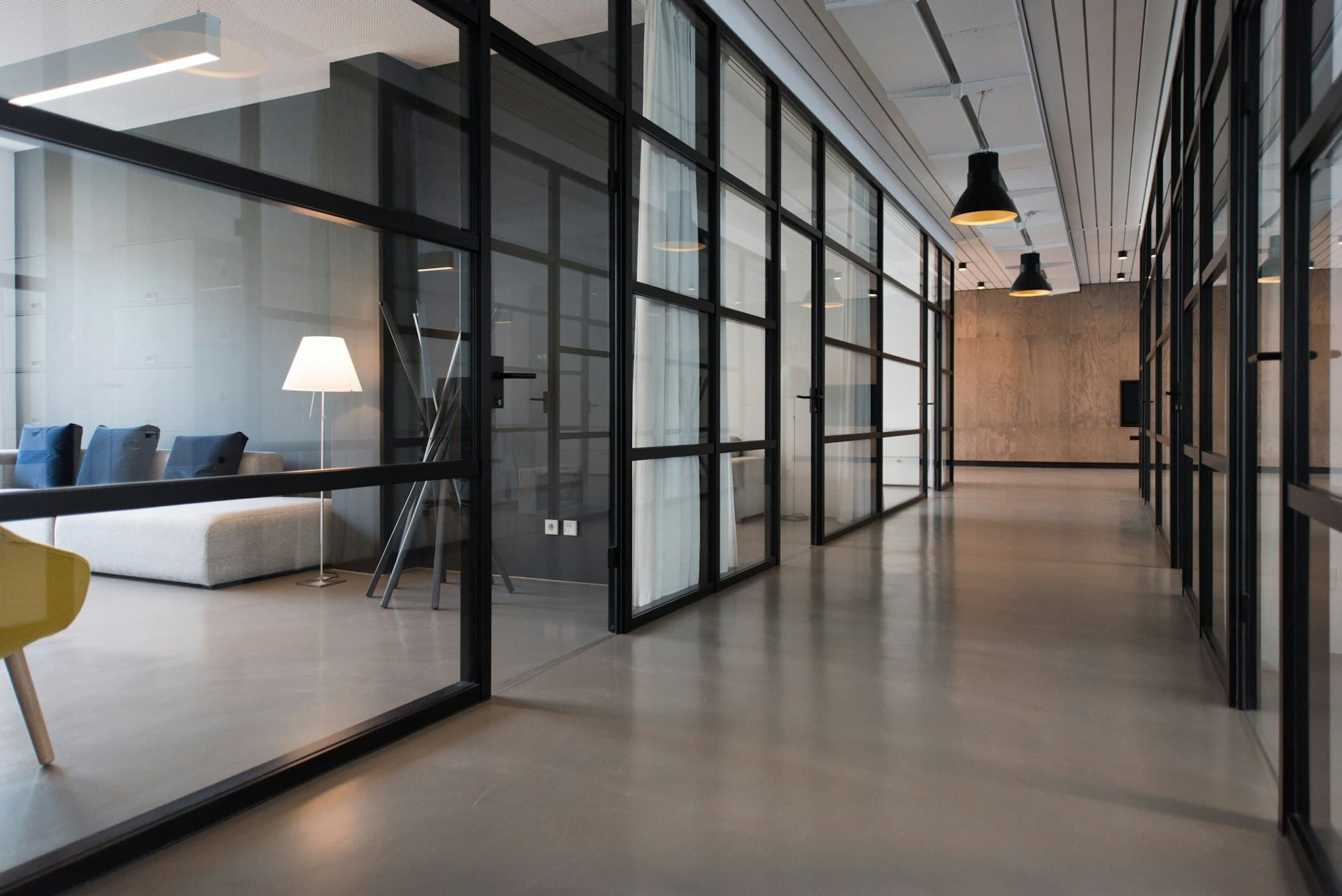 Long corridor lined with black-framed glass partitions and a polished floor